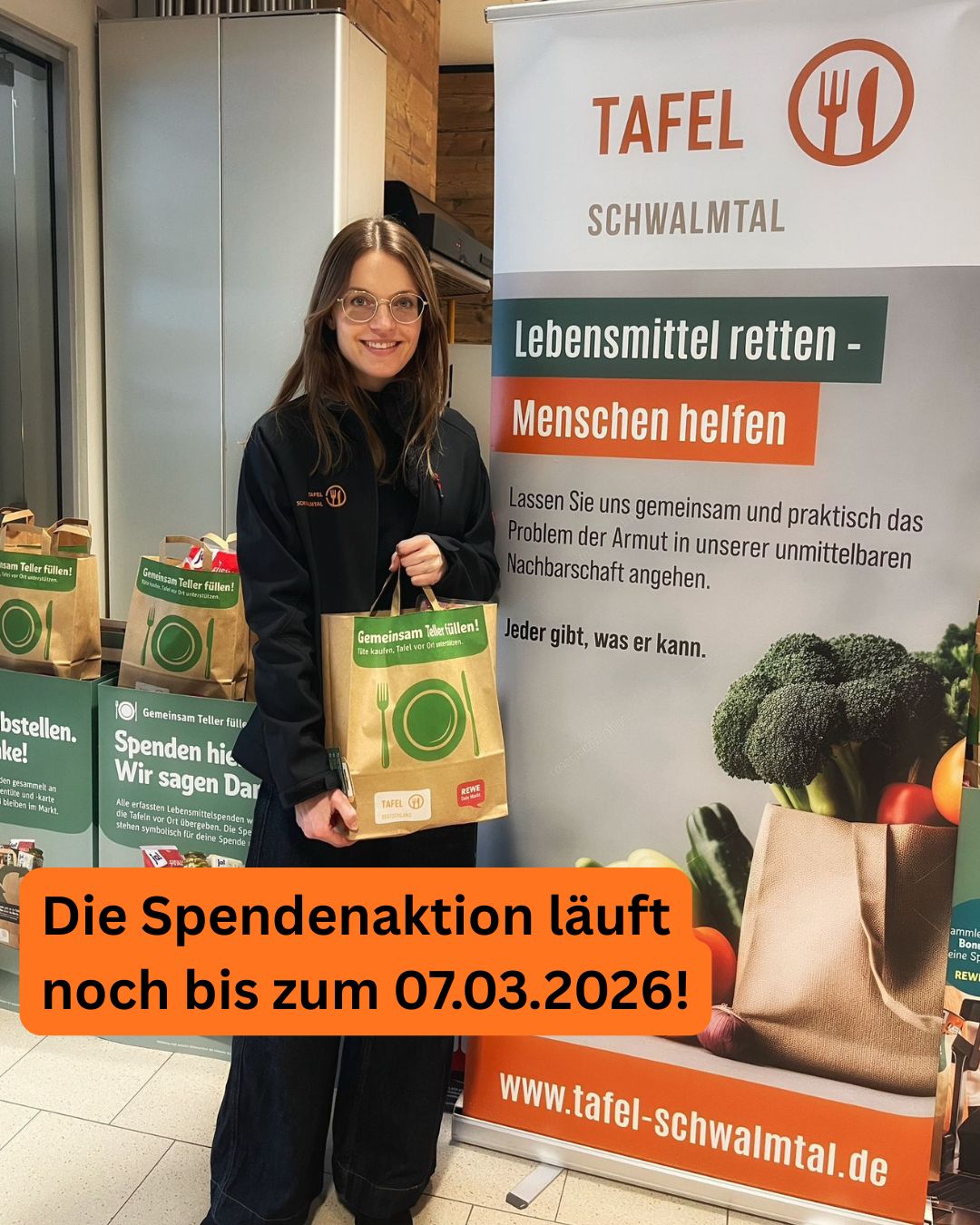 Eine junge Frau mit braunen Haaren lächelt freundlich und hält eine grüne Papiertüte vor einem Aufsteller mit der Aufschrift Lebensmittel retten Menschen helfen in einem hellen Raum