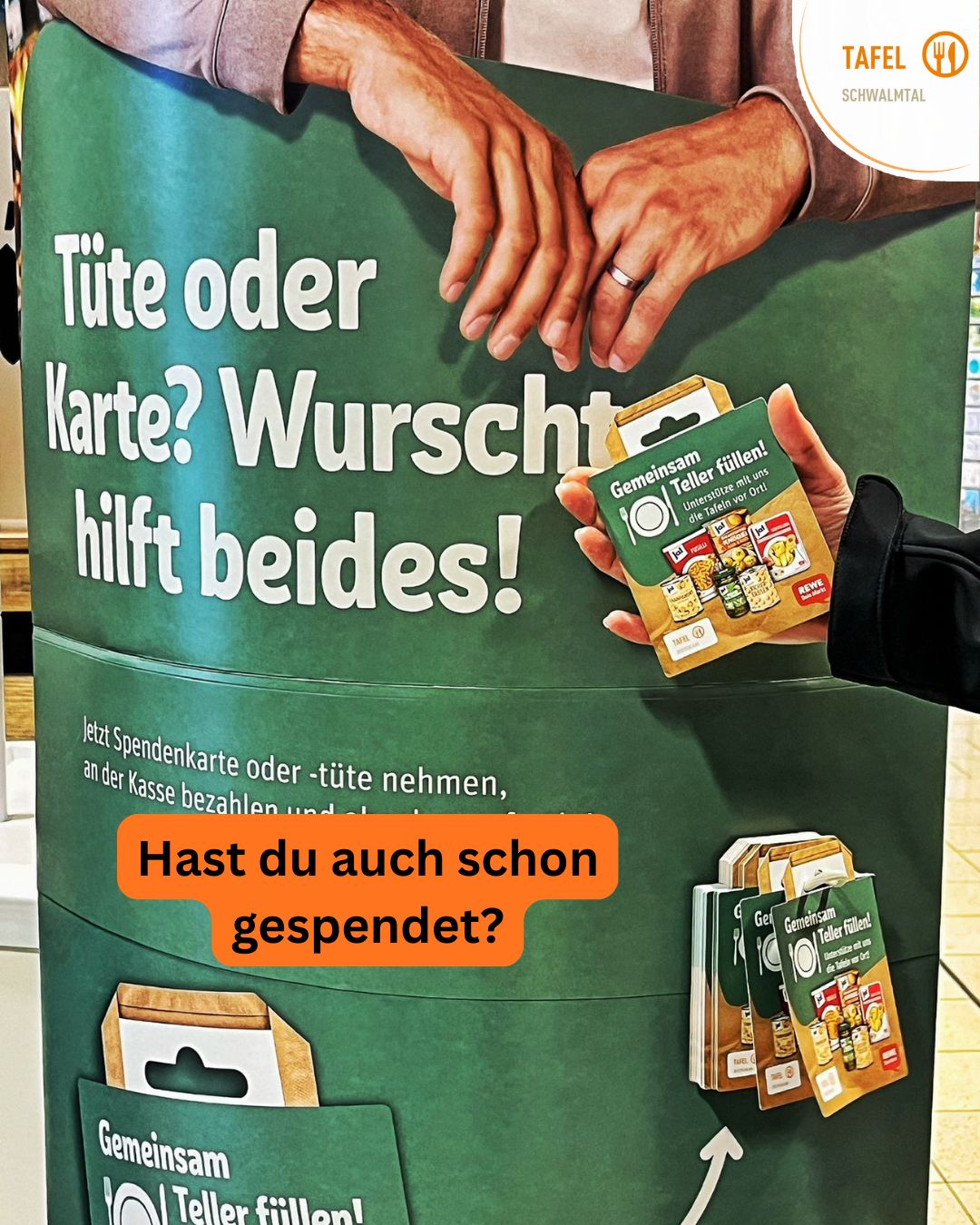 Ein Werbeaufsteller zeigt eine grüne Spendenaktion mit großem Schriftzug und Karten.