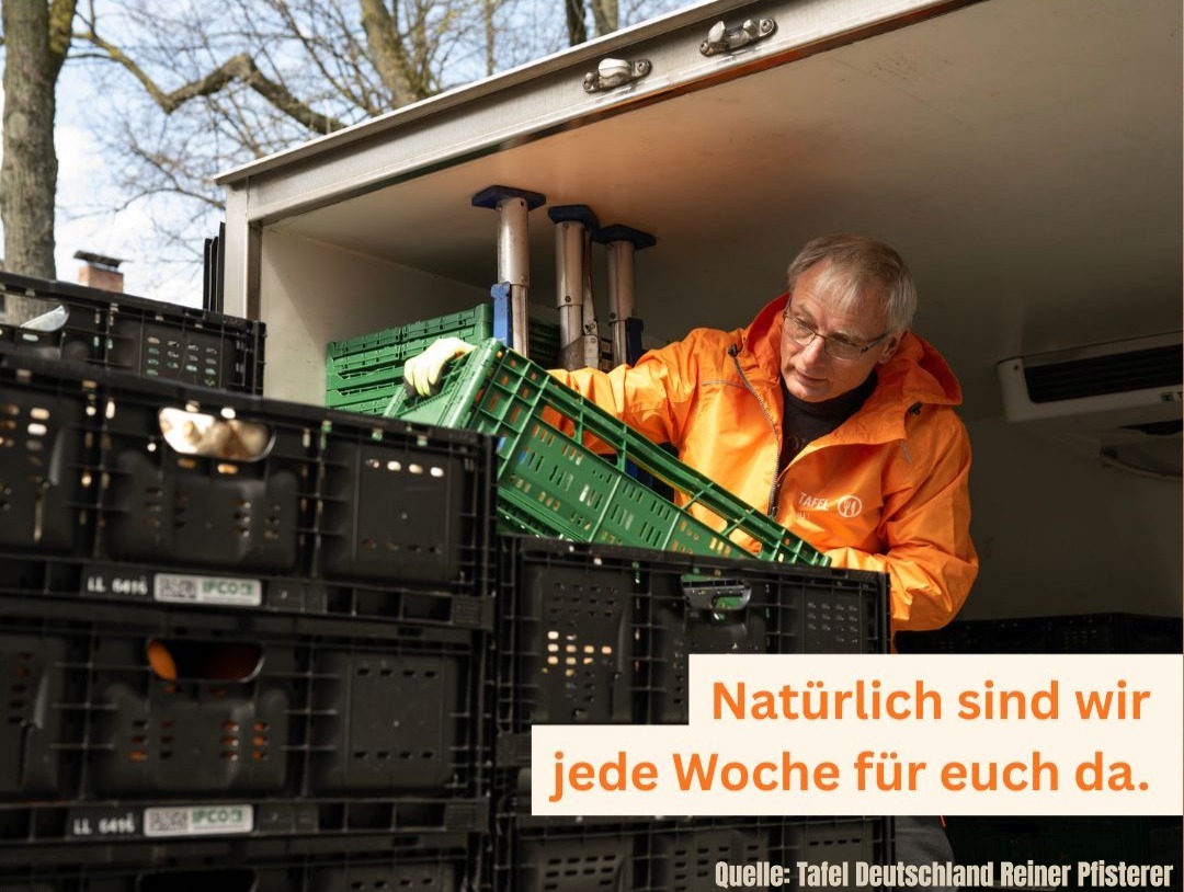 Eine Person mit orangefarbener Jacke lächelt beim Entladen von grünen Kisten